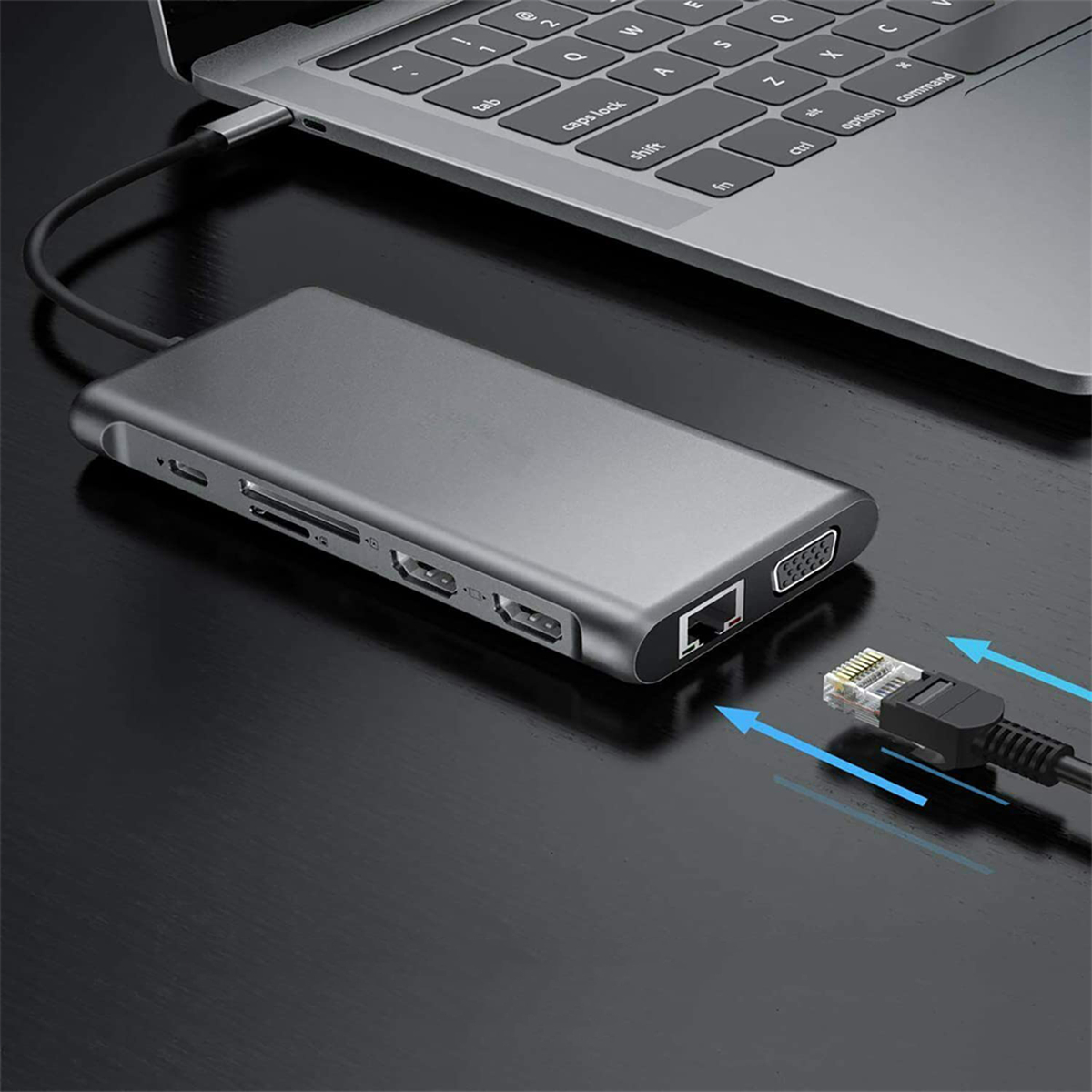 Ein silberner Hub, der mit einem Laptop und einem Ethernet-Kabel verbunden ist. Schwarzer Schreibtischhintergrund.