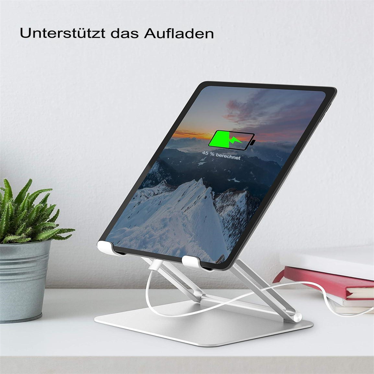 Ein Tablet auf einem silbernen Ständer mit einem Bergmotiv. Der Bildschirm zeigt den Ladefortschritt.