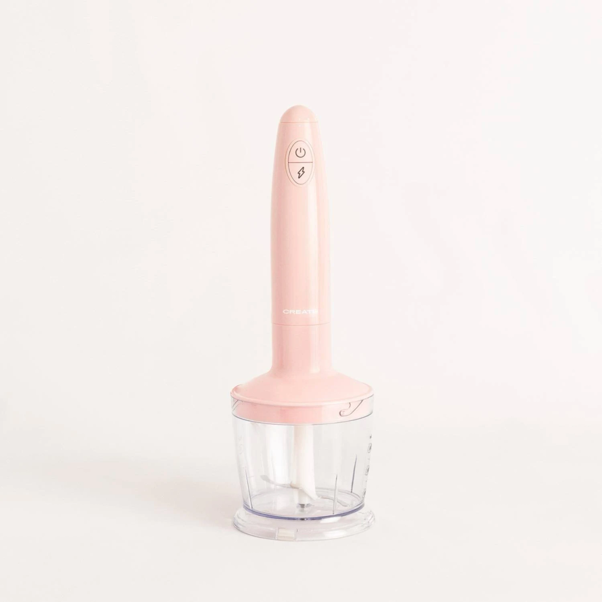 Una batidora de inmersión CREATE rosa con un recipiente transparente sobre fondo blanco.