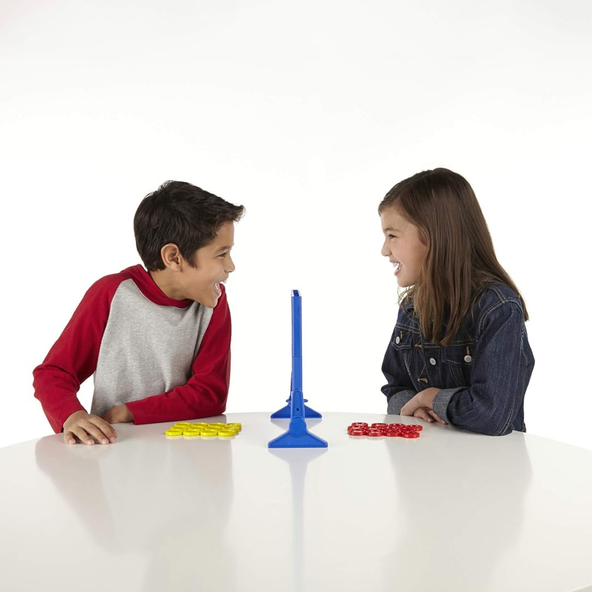 Zwei Kinder, ein Junge und ein Mädchen, stehen sich gegenüber und spielen ein Spiel auf einem weißen Tisch.