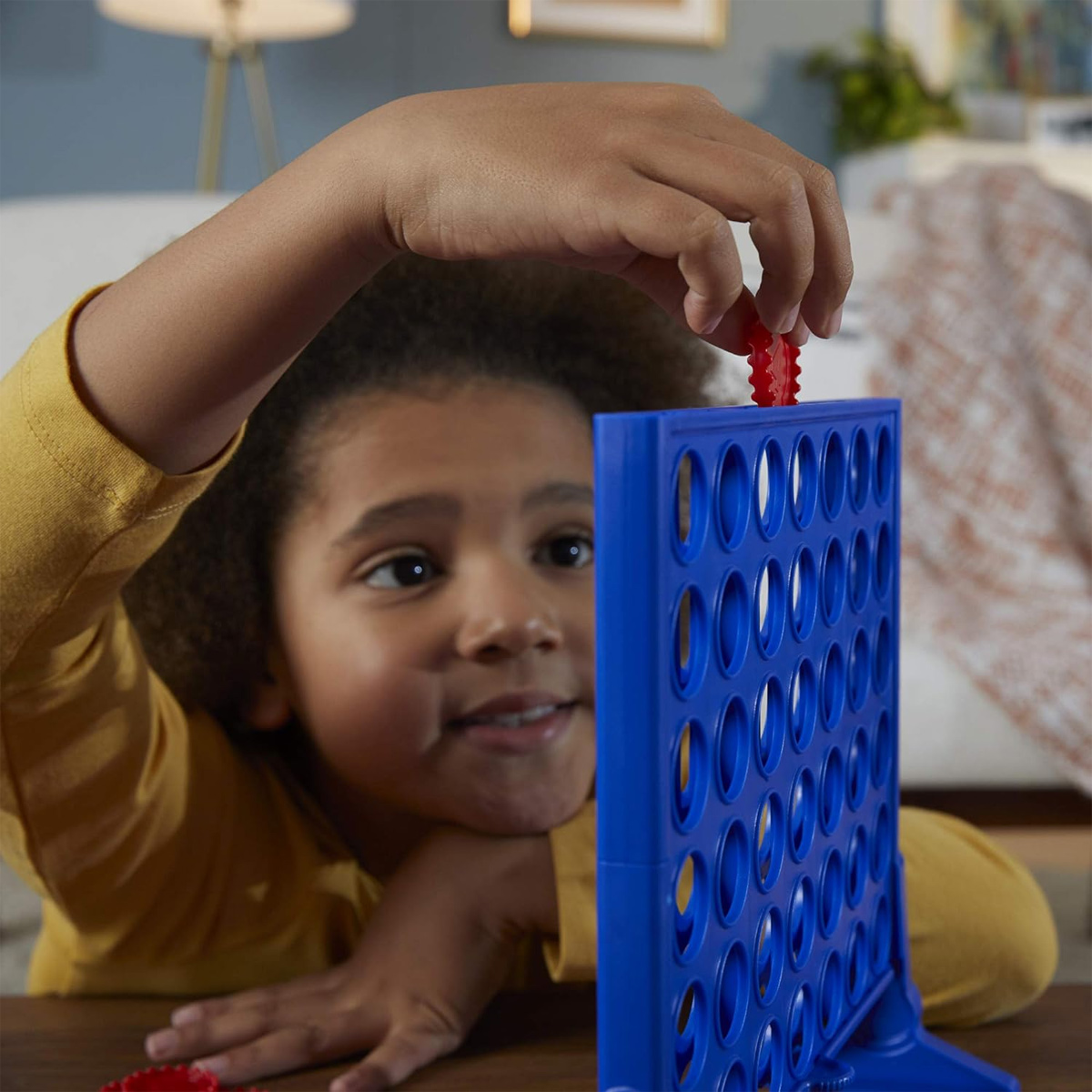 Ein Kind spielt Connect Four und legt eine rote Scheibe in das Brett.