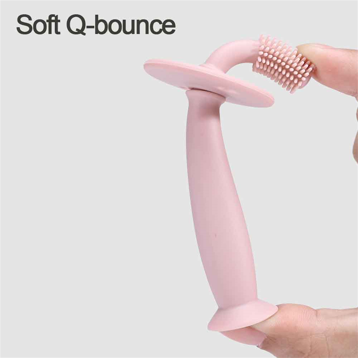 Rosa Baby-Zahnbürste wird von einer Hand gehalten. Soft Q-bounce Text.