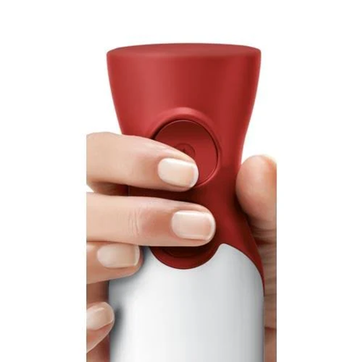 Una mano che preme un pulsante rosso su un frullatore rosso e bianco. Primo piano sulla mano.