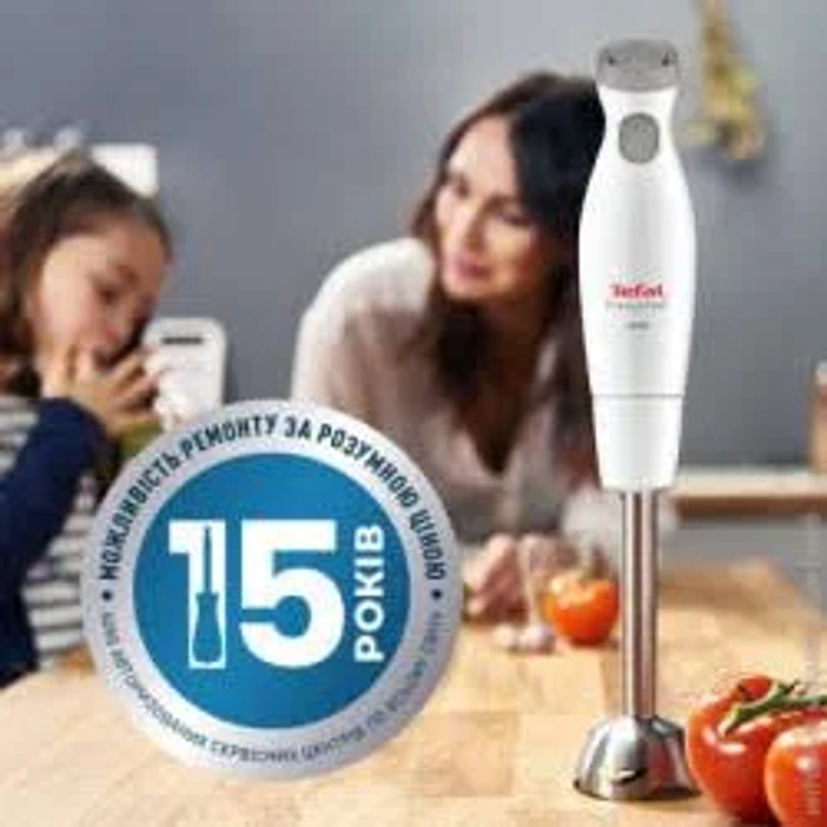 Een witte staafmixer, tomaten en een label met de tekst '15 rokiv'.