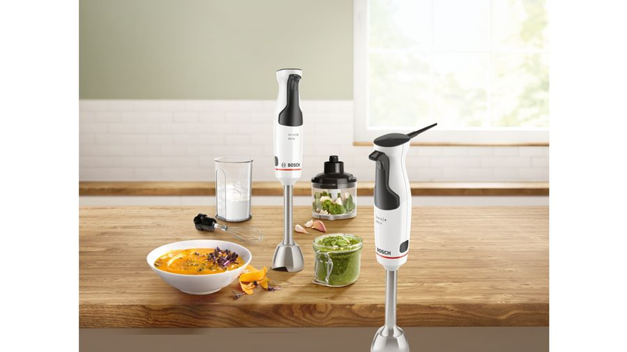 Srebrny mikser stojący z misą i przystawkami na blacie kuchennym.