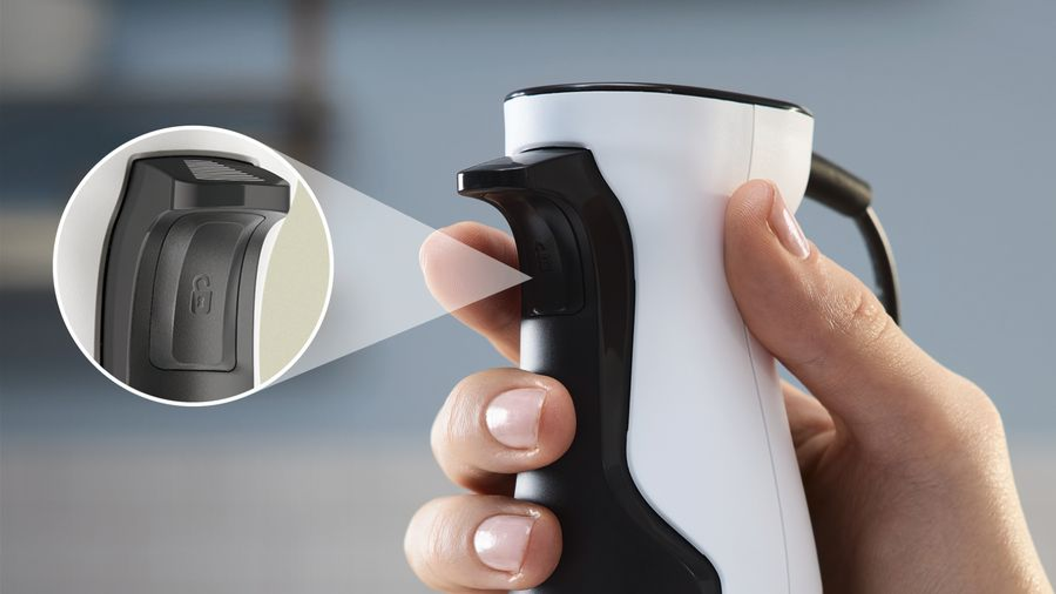 Dłoń trzyma czarno-biały blender. Przycisk widoczny jest w zbliżeniu.