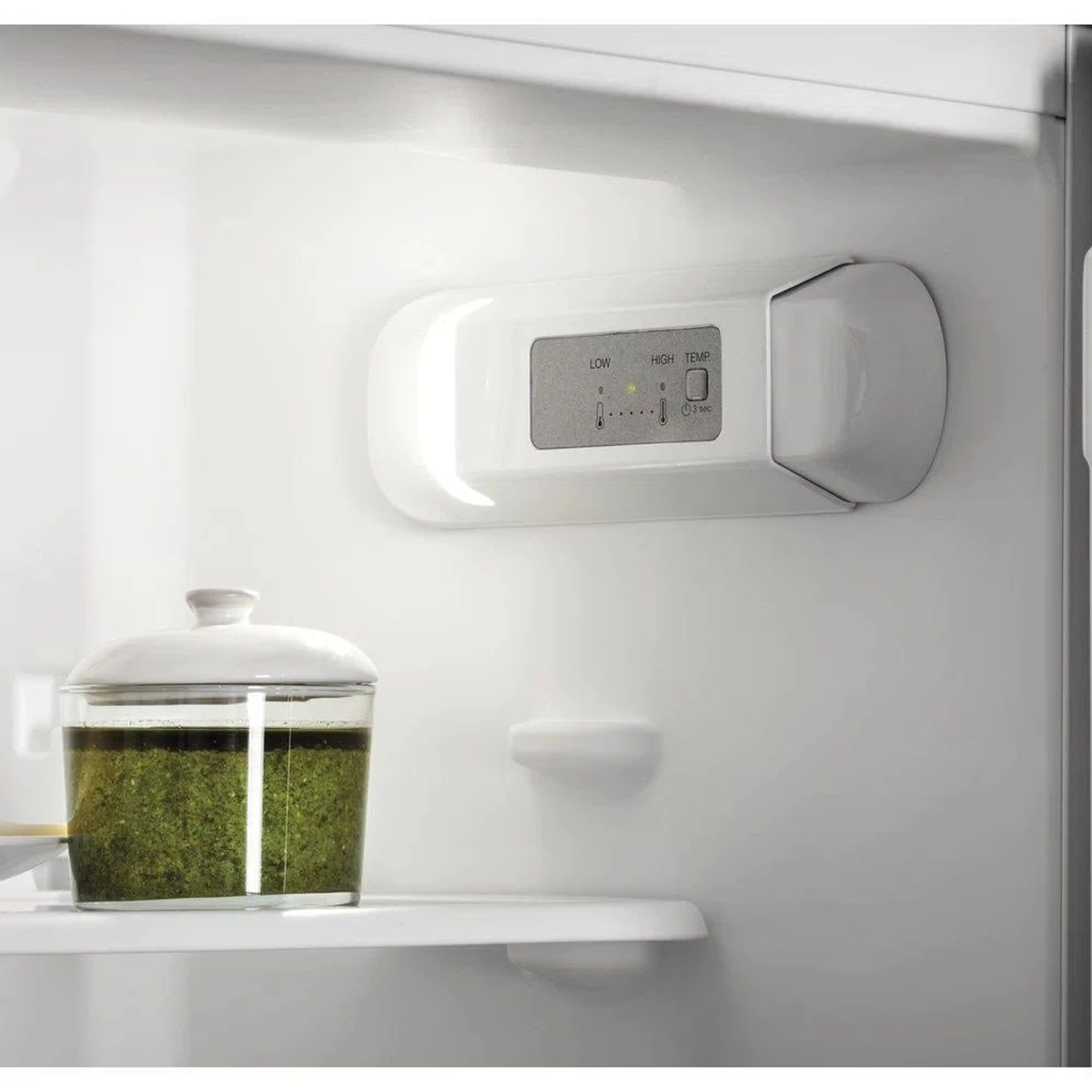 Interno di un frigorifero con un barattolo di pesto verde e comandi della temperatura.
