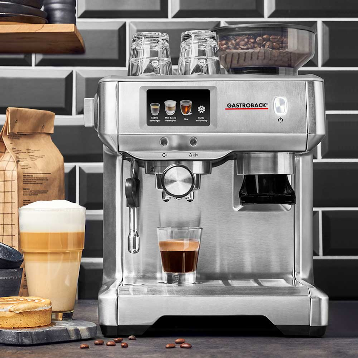 Srebrny ekspres do espresso ze szklanką espresso i mleka. Ziarna kawy na wierzchu.