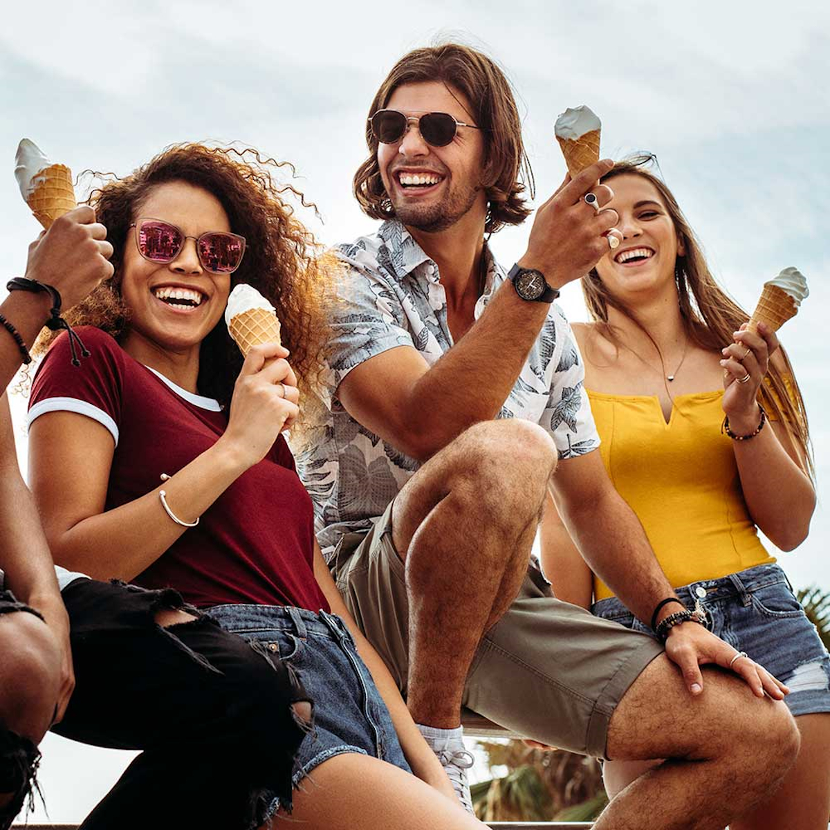Drei Leute lächeln und essen im Freien Eiswaffeln.