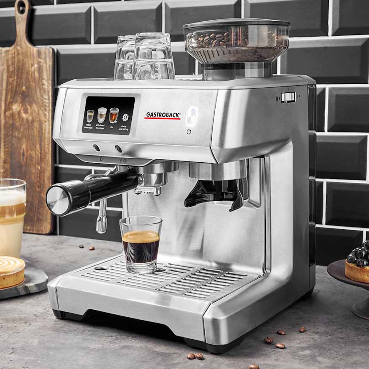 Srebrny ekspres do kawy z filiżanką kawy i pojemnikiem na ziarna kawy na górze.