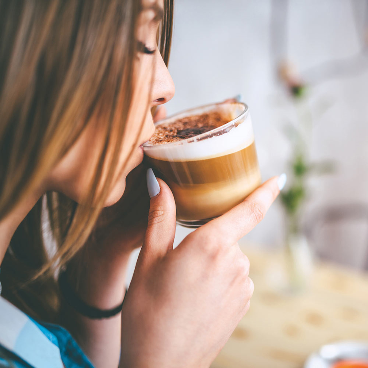 Kobieta pije cappuccino ze szklanki, zbliżenie.