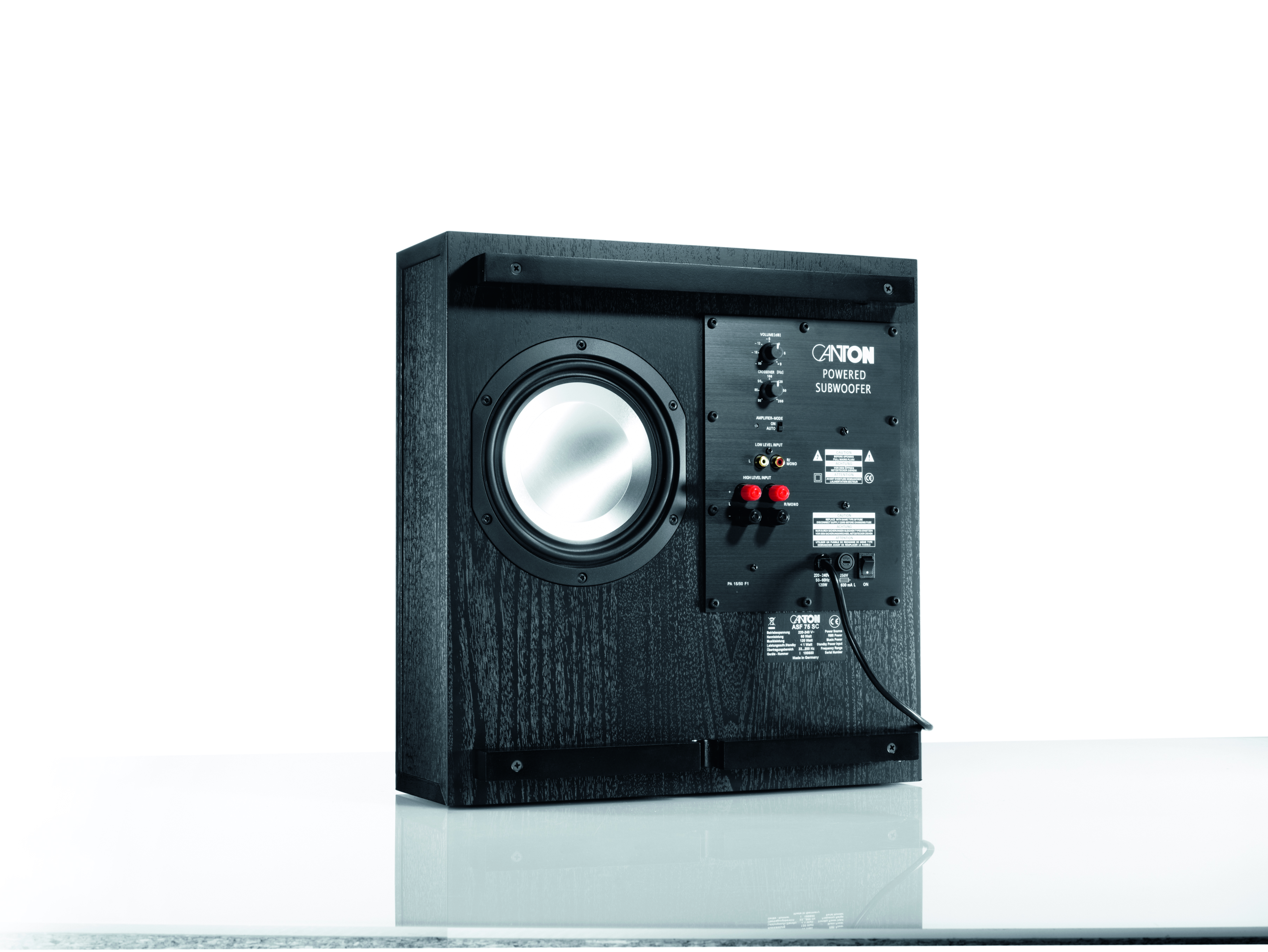 Schwarzer Aktiv-Subwoofer auf weißer Oberfläche. Rückseite des Lautsprechers sichtbar.