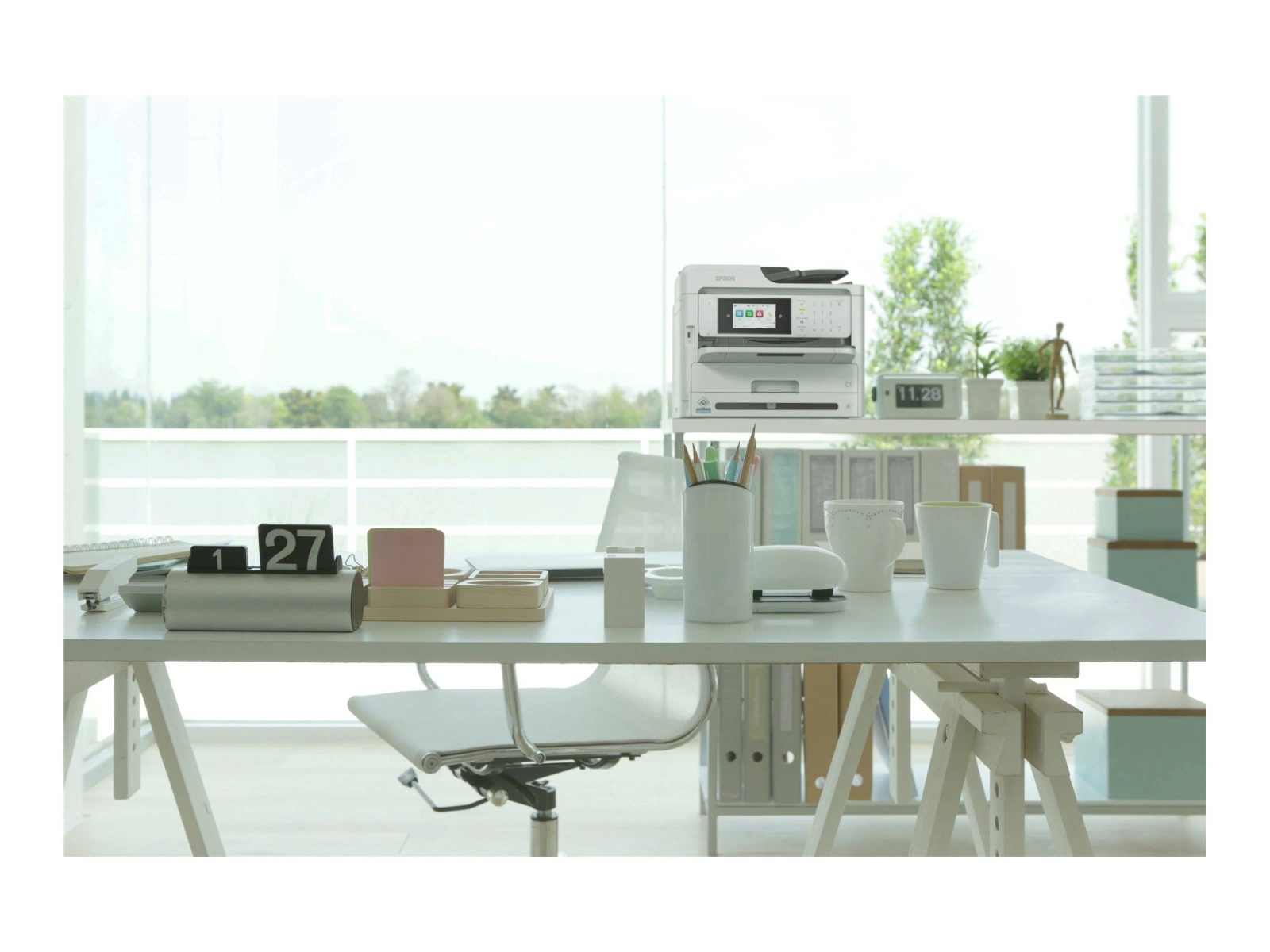 Biurko z drukarką, kalendarzem i artykułami biurowymi.