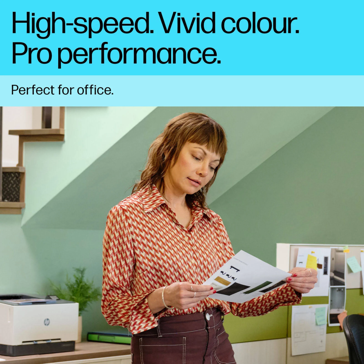 Kobieta w koszuli we wzory czyta dokument w biurze, w pobliżu drukarki.