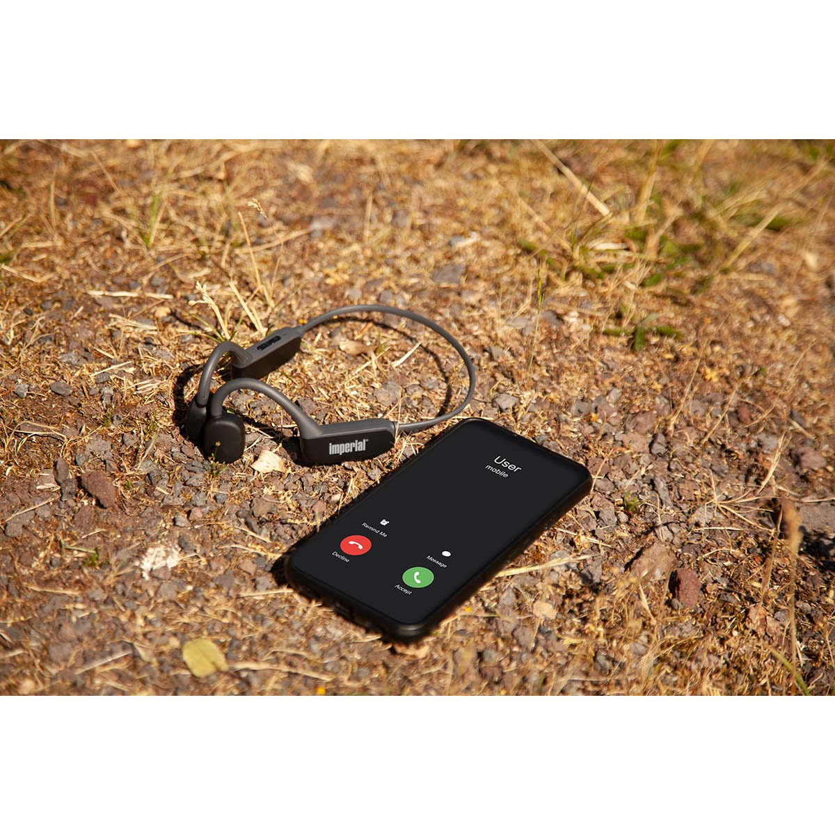 Słuchawki przewodnictwa kostnego i smartfon pokazujący połączenie przychodzące na powierzchni ziemi.