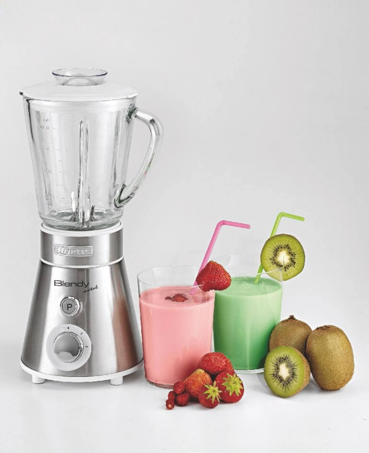 Licuadora y dos vasos de batidos con frutas y pajitas.