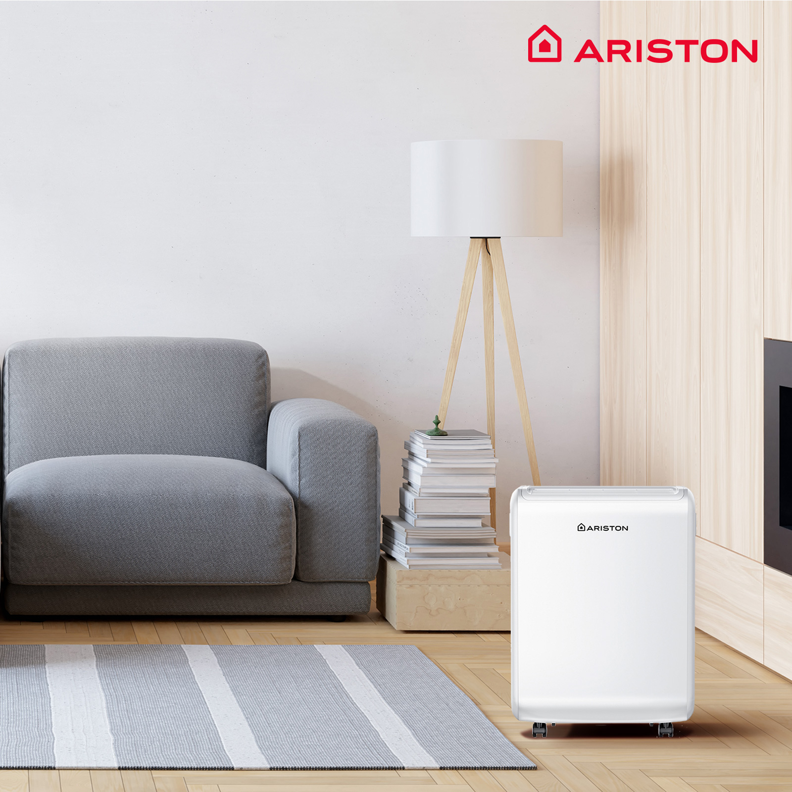 Una sala de estar con un purificador de aire blanco de Ariston, un sofá gris y una lámpara.