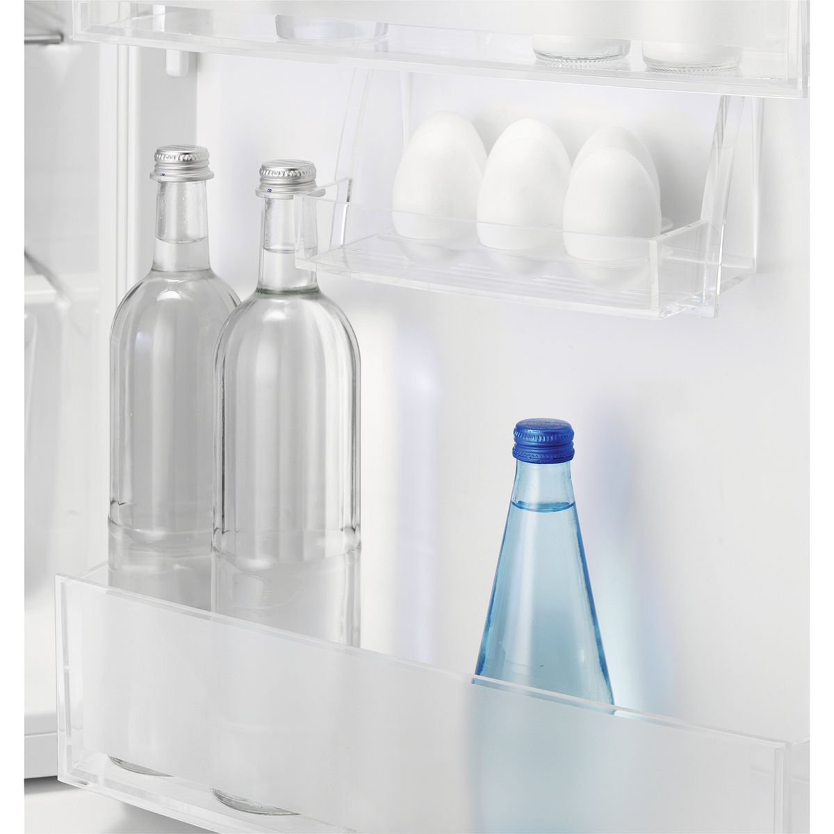 Interno del frigorifero con bottiglie e contenitori. Due bottiglie di vetro, una con tappo blu. Sfondo bianco.