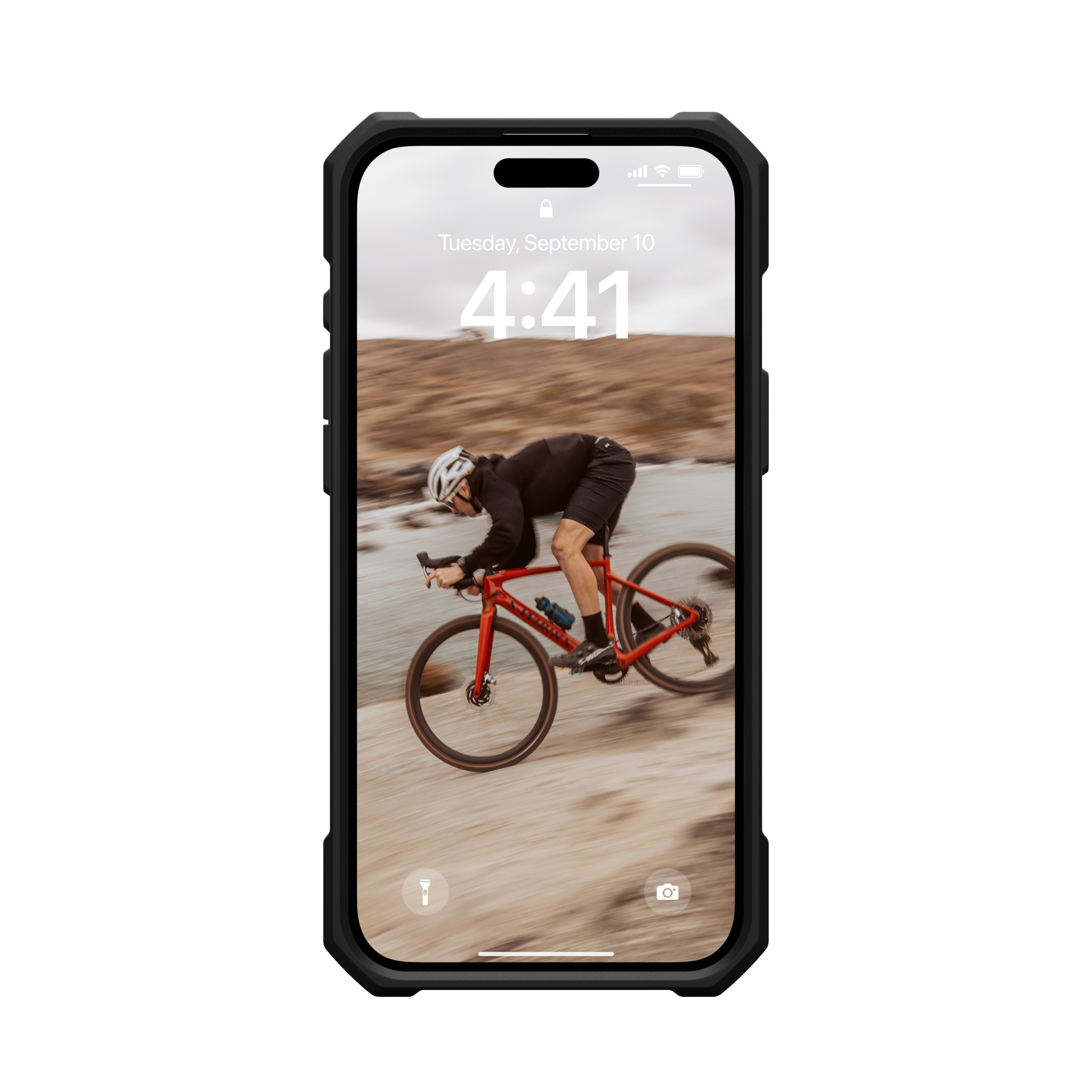 Ein Telefon in einer Hülle zeigt einen Radfahrer auf einem roten Fahrrad, Bewegungsunschärfe, auf felsigem Gelände.