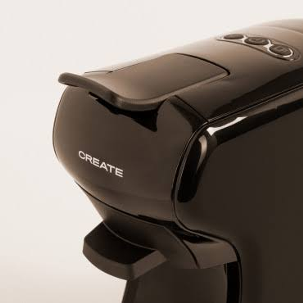 Primer plano de una cafetera negra con la palabra 'CREATE' escrita. La máquina tiene un diseño elegante.