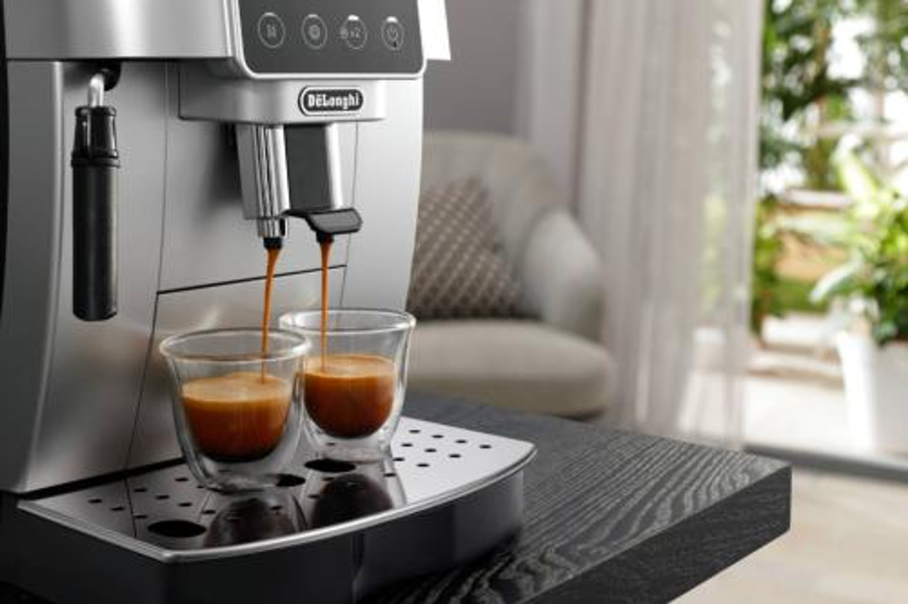 Ekspres do espresso DeLonghi dozujący kawę do dwóch szklanych filiżanek.