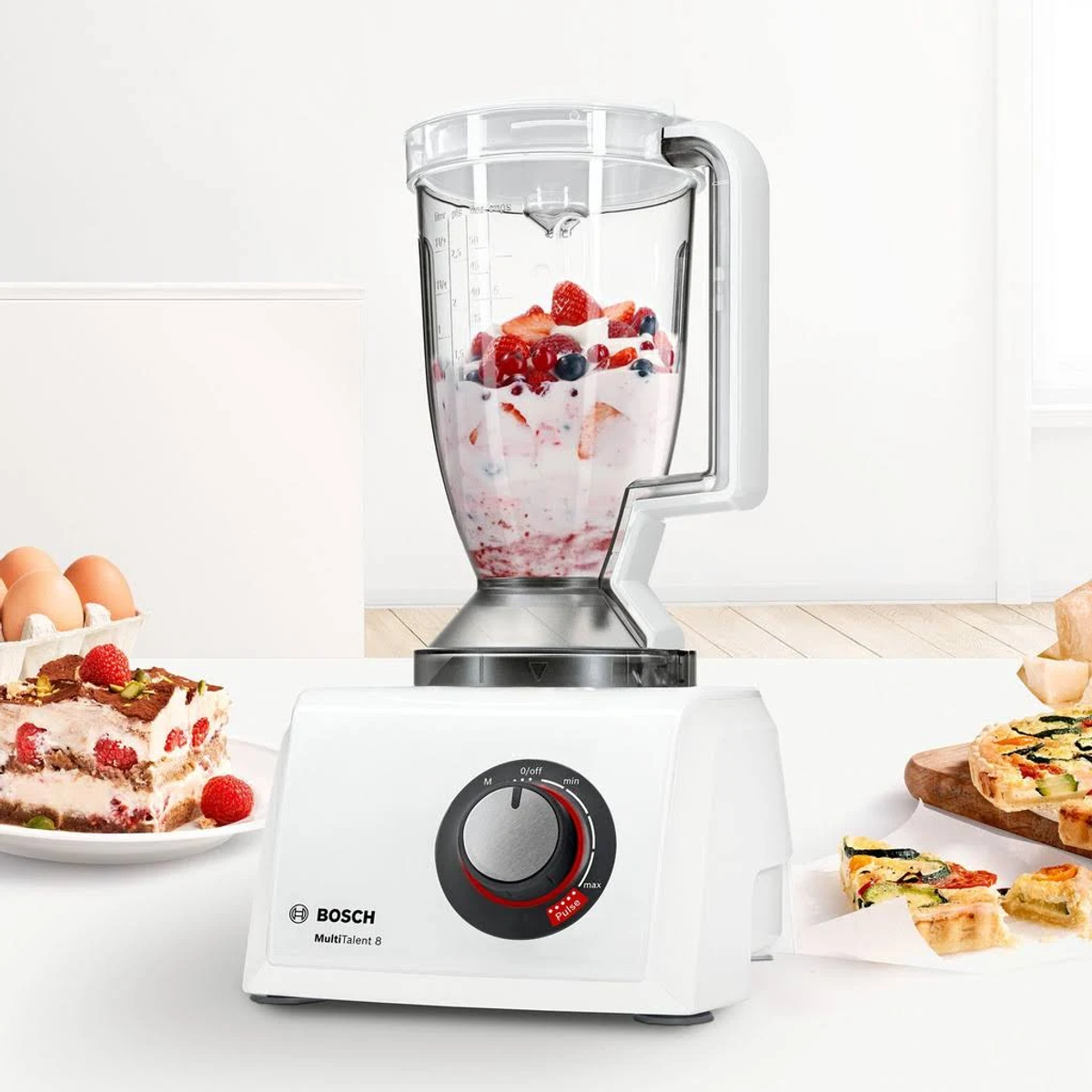 Licuadora blanca y transparente con frutas mixtas y crema dentro.