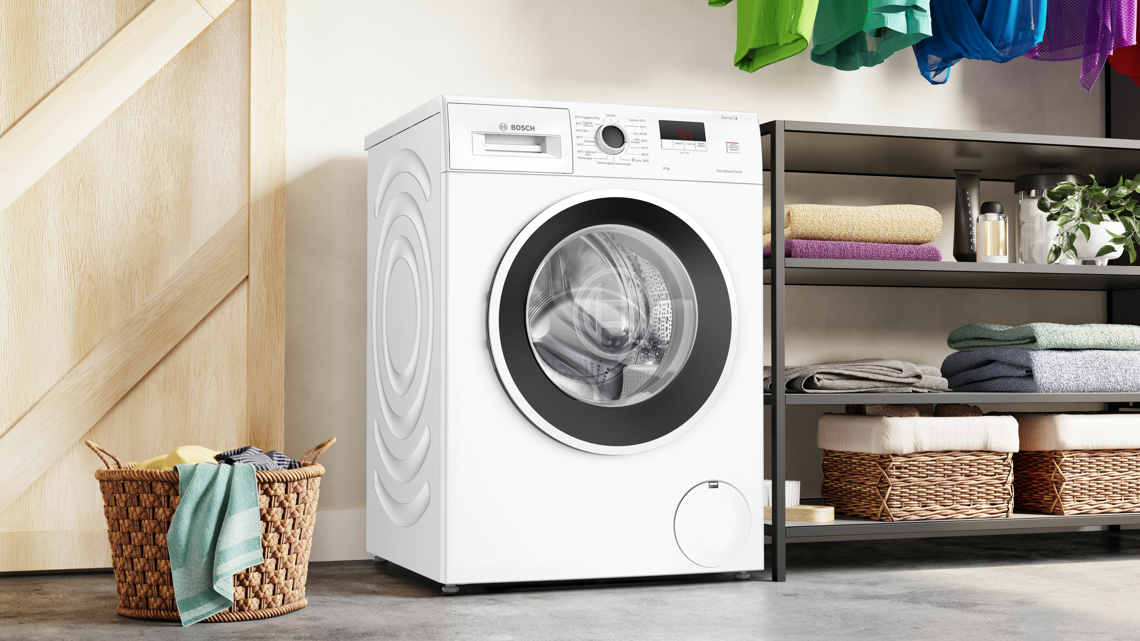 Witte wasmachine naast deur en plank met handdoeken.