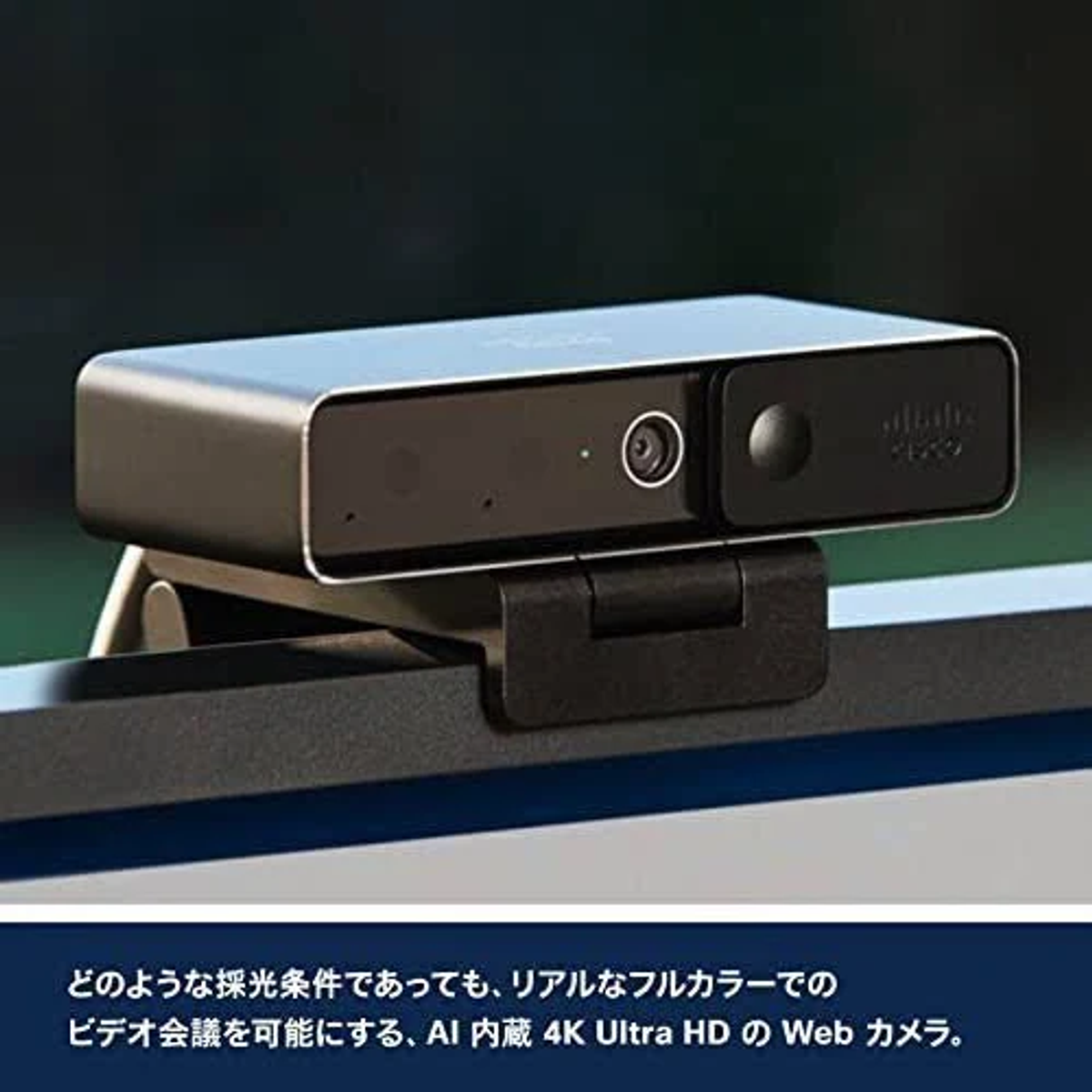 Kamera internetowa na biurku. Jest czarna, ma obiektyw i jest zamontowana na monitorze.