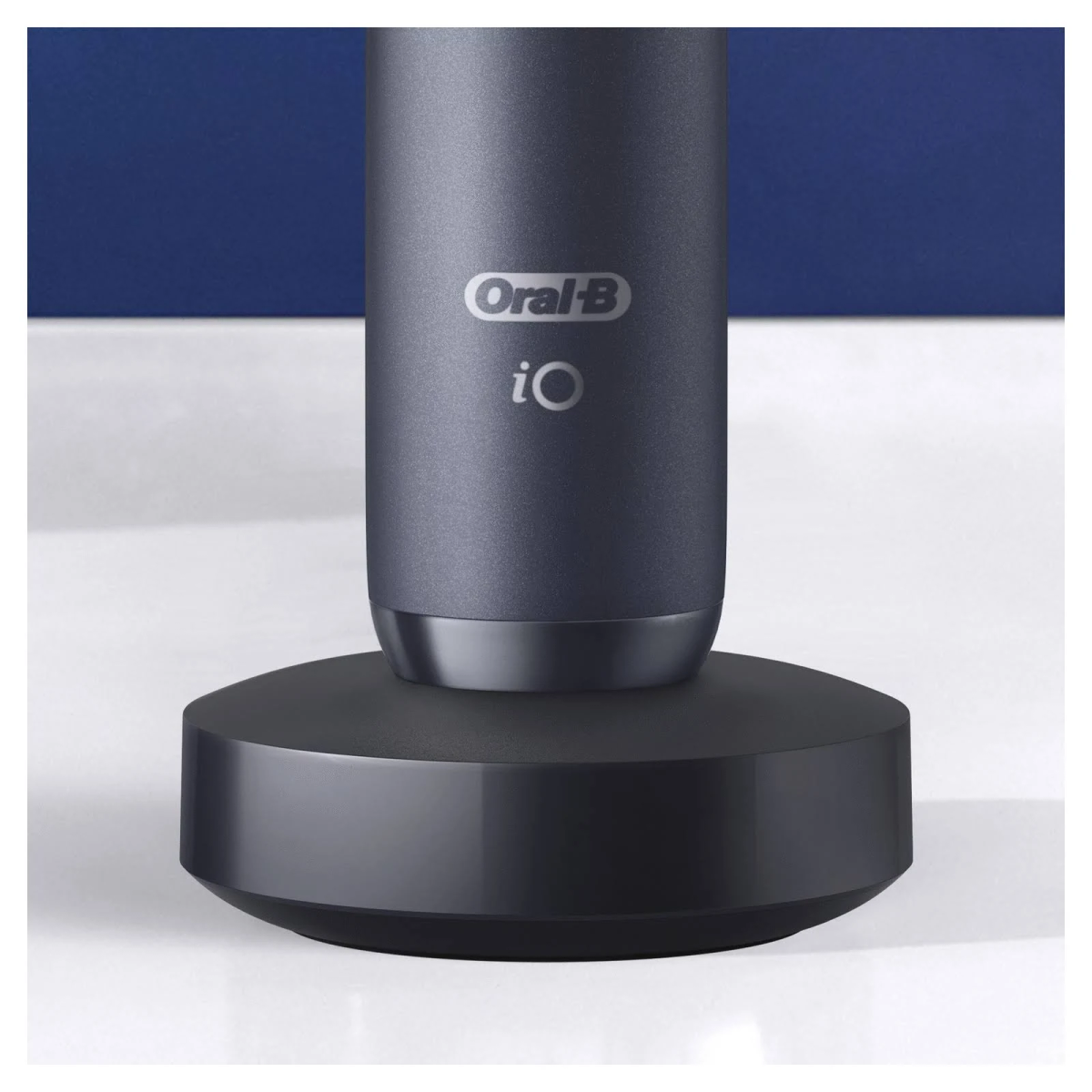 Cepillo de dientes eléctrico Oral-B iO en su base de carga. El cepillo es gris oscuro, la base negra.