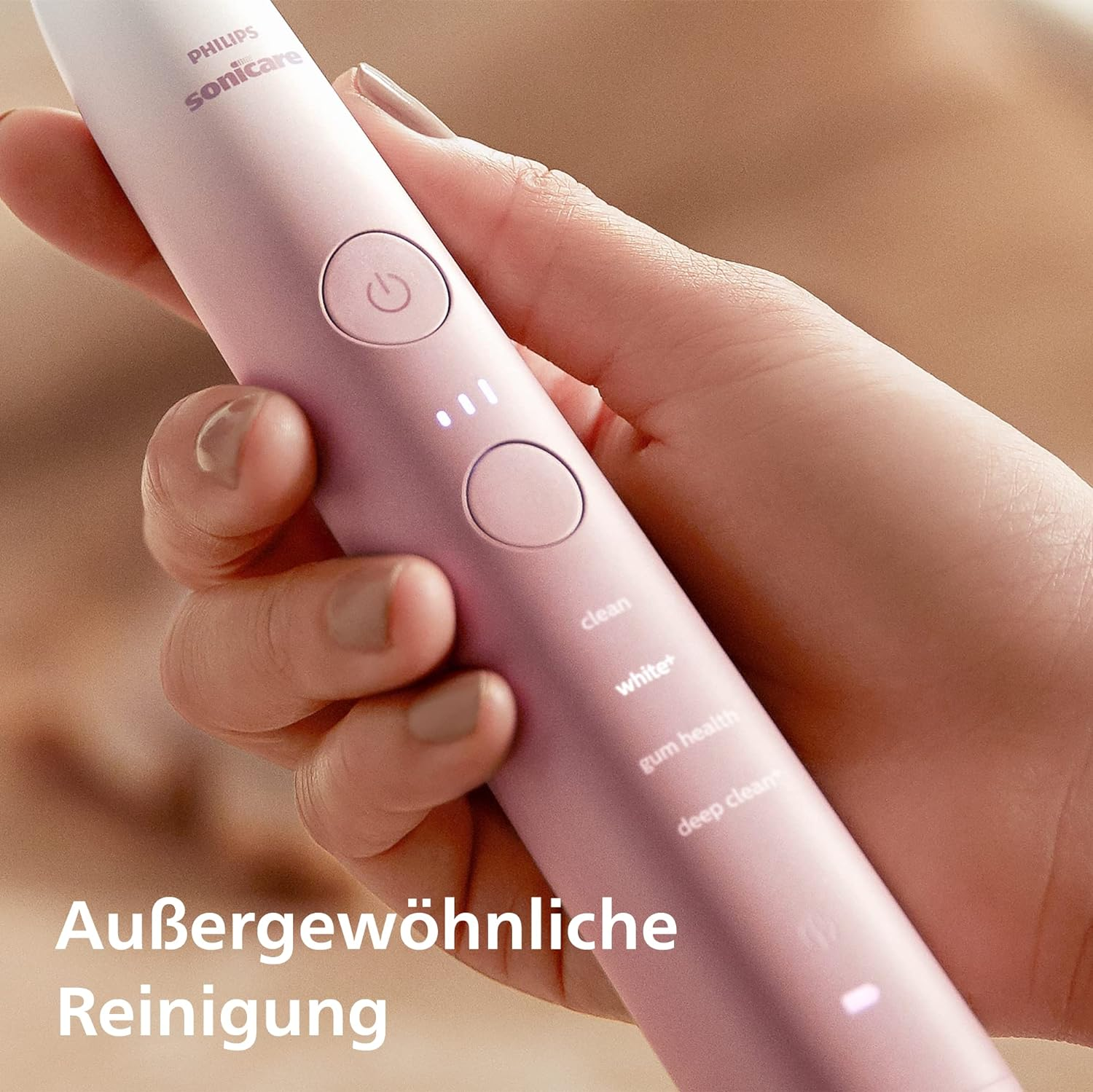 Una mano che tiene uno spazzolino elettrico Philips Sonicare rosa. Lo spazzolino è acceso e mostra le impostazioni.