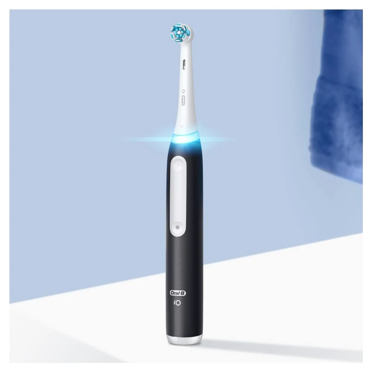 Black and white electric toothbrush with a blue light, white background.