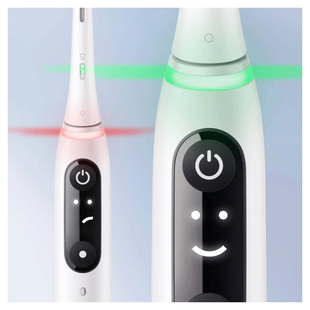 Primo piano di due spazzolini elettrici bianchi. Uno mostra una luce rossa, l'altro una luce verde. Pulsante di accensione visualizzato.