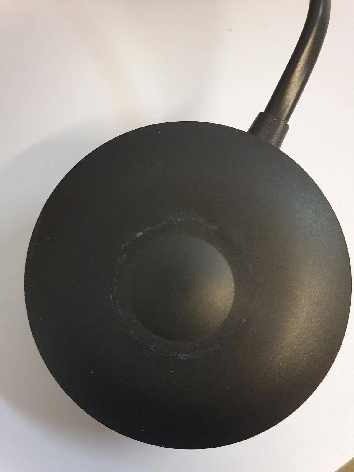 Schwarzes, rundes Gerät mit Netzkabel. Das Gerät ist kreisförmig mit leicht erhöhtem Zentrum.