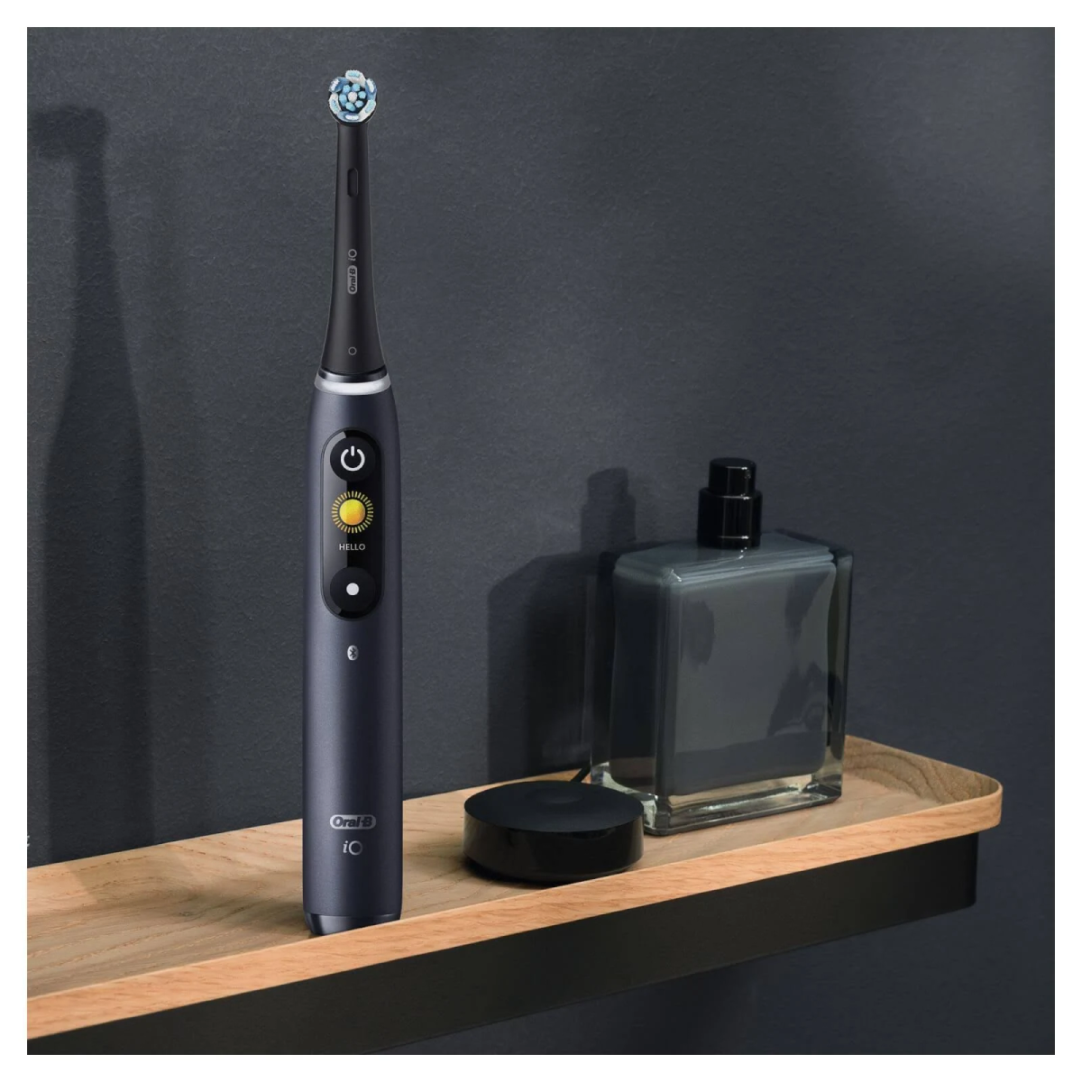 Un cepillo de dientes eléctrico Oral-B iO, azul marino, en una estantería con una botella y un cargador.