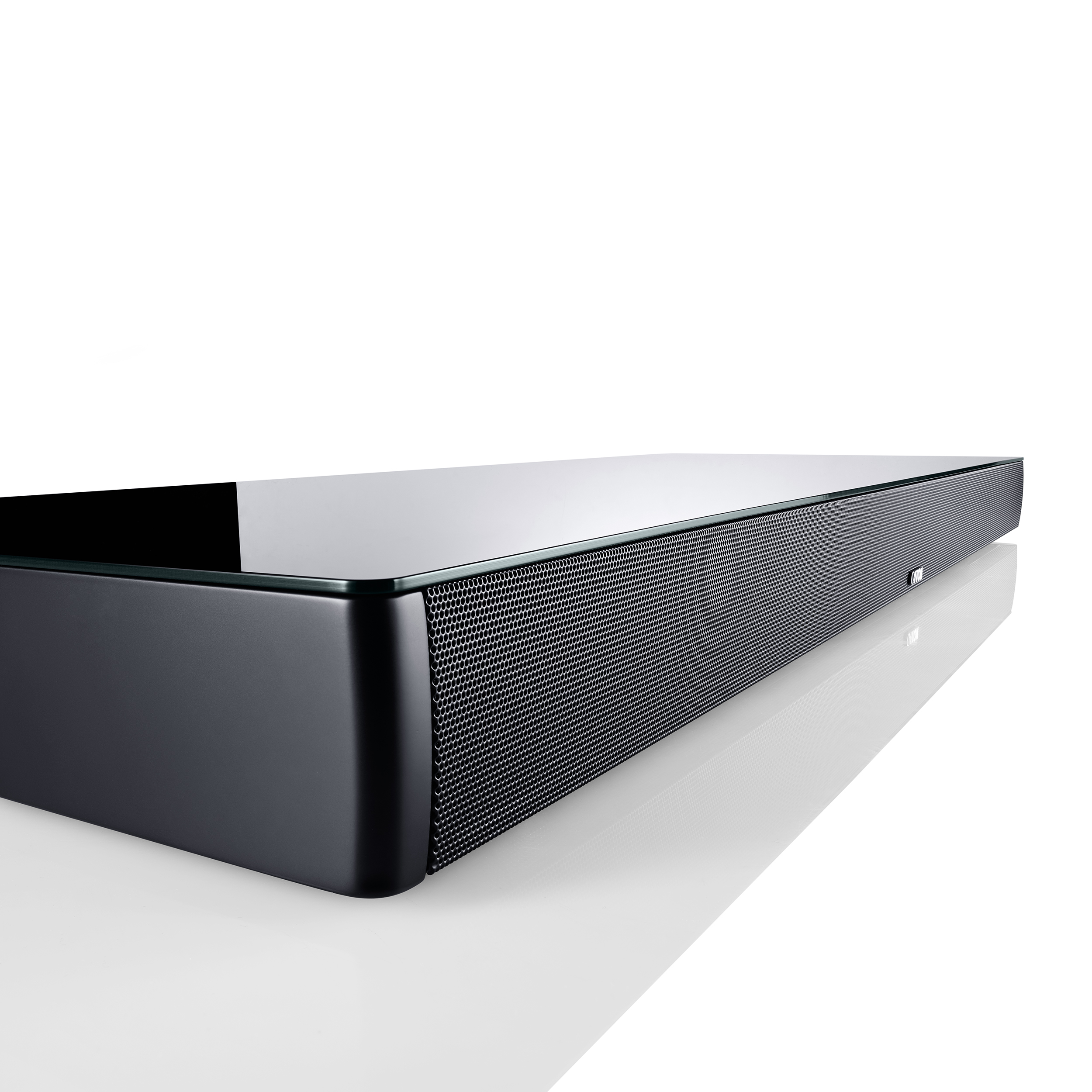Ein schwarzer Soundbar-Lautsprecher auf einer weißen Oberfläche. Die Oberfläche reflektiert den Lautsprecher.