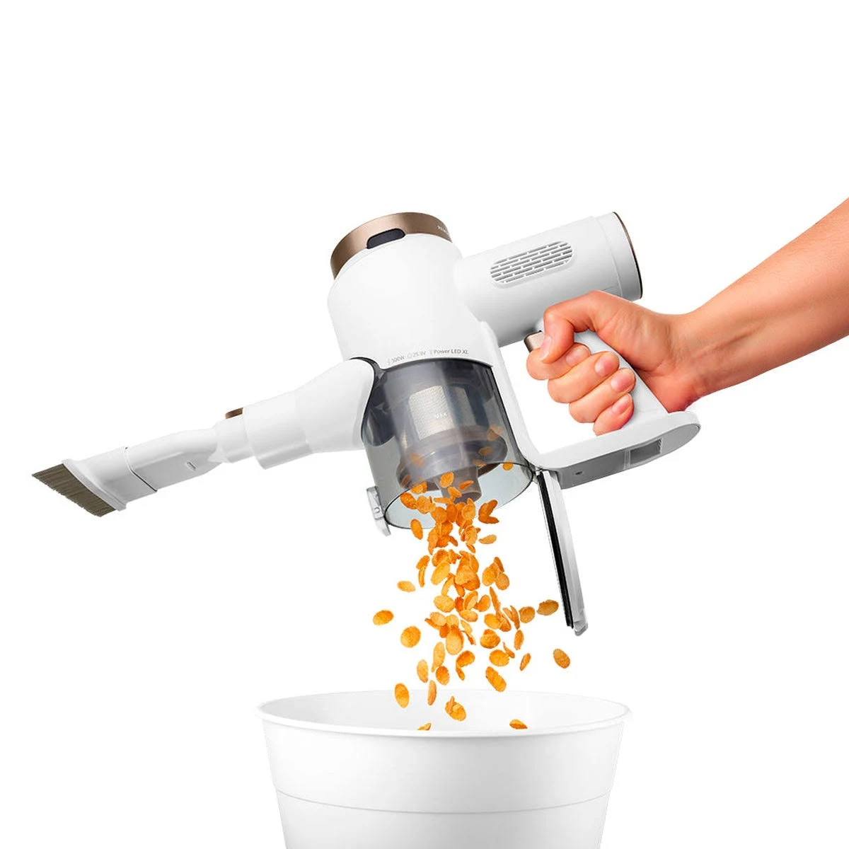 Aspirapolvere portatile bianco e oro con cereali che cadono in un bidone bianco.