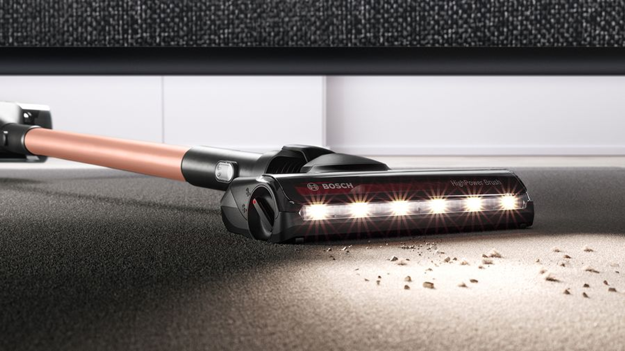 Zbliżenie głowicy odkurzacza na dywanie, widoczne światła i zanieczyszczenia.