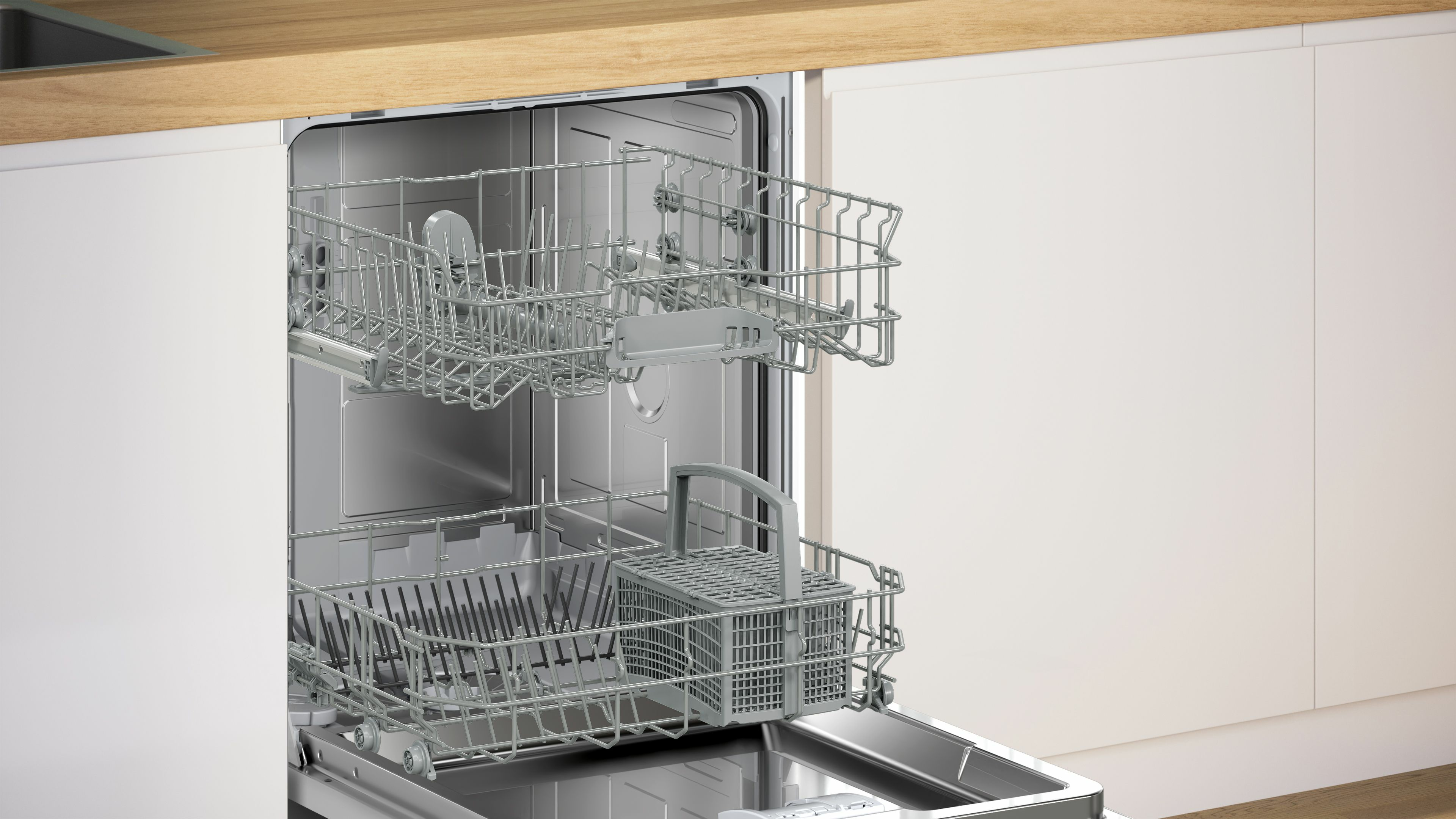 Otwarta zmywarka z dwoma półkami, w białej szafce kuchennej.