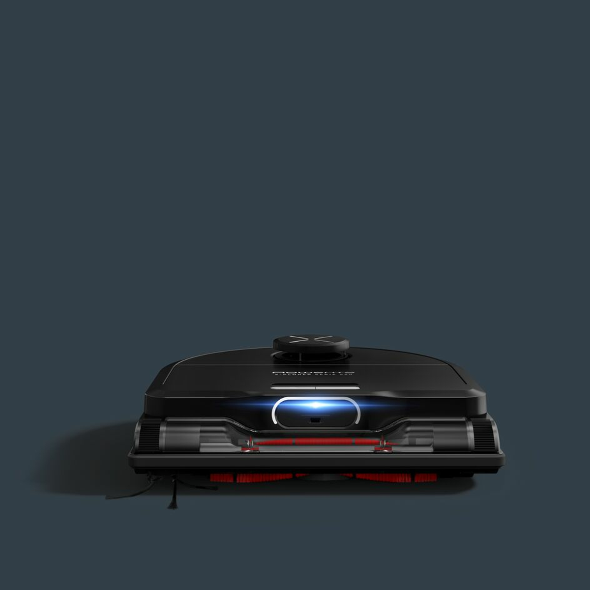 Un robot aspirapolvere nero su uno sfondo scuro. Spazzole e luci rosse sono visibili.