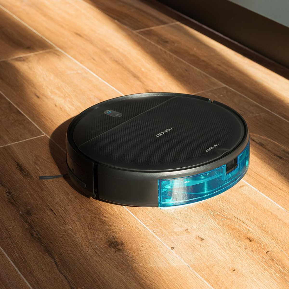 Robot sprzątający, czarny, na drewnianej podłodze. Robot jest okrągły, ze zbiornikiem na wodę i marką CONGA.
