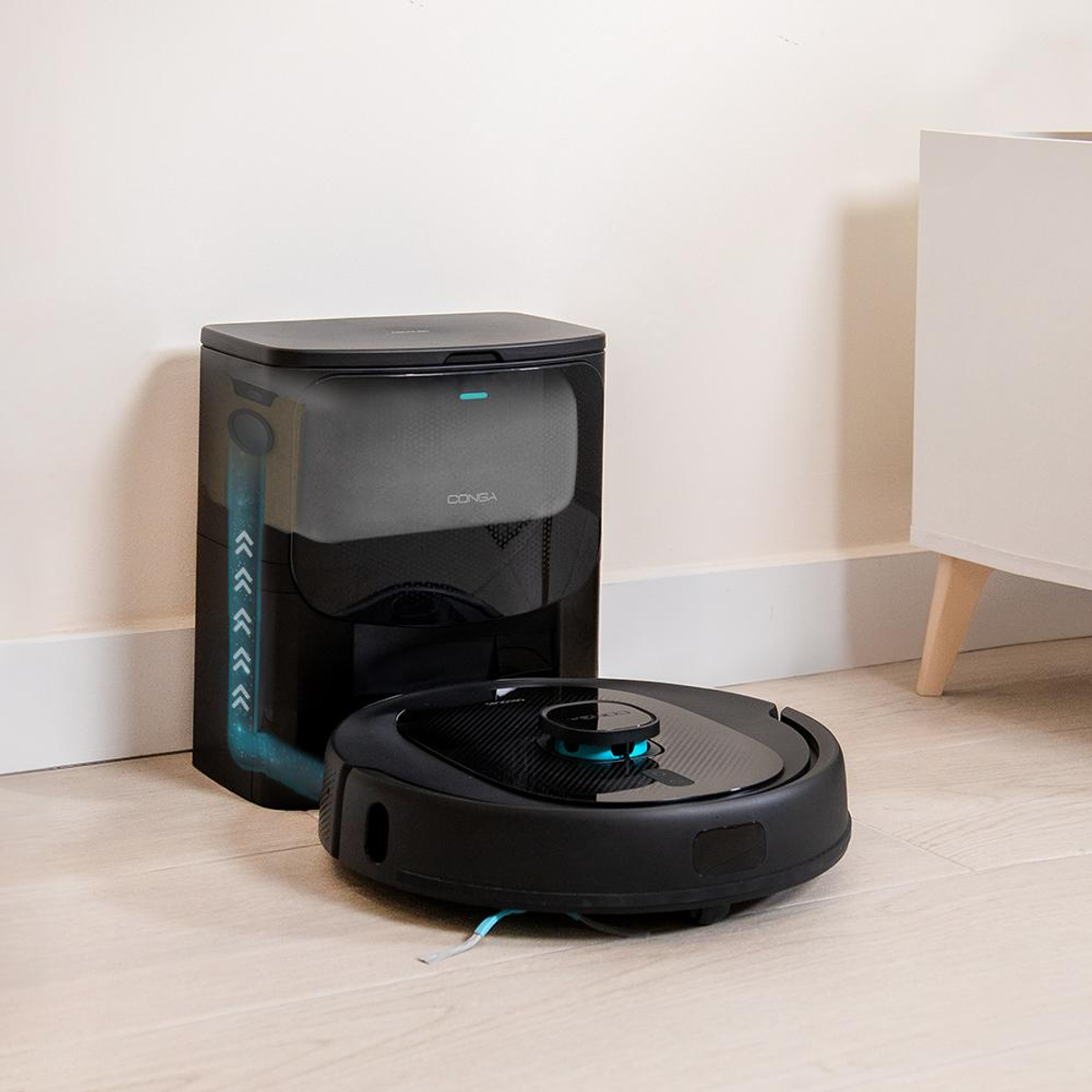 Un robot aspirapolvere nero e la sua stazione di ricarica sono su un pavimento in legno.