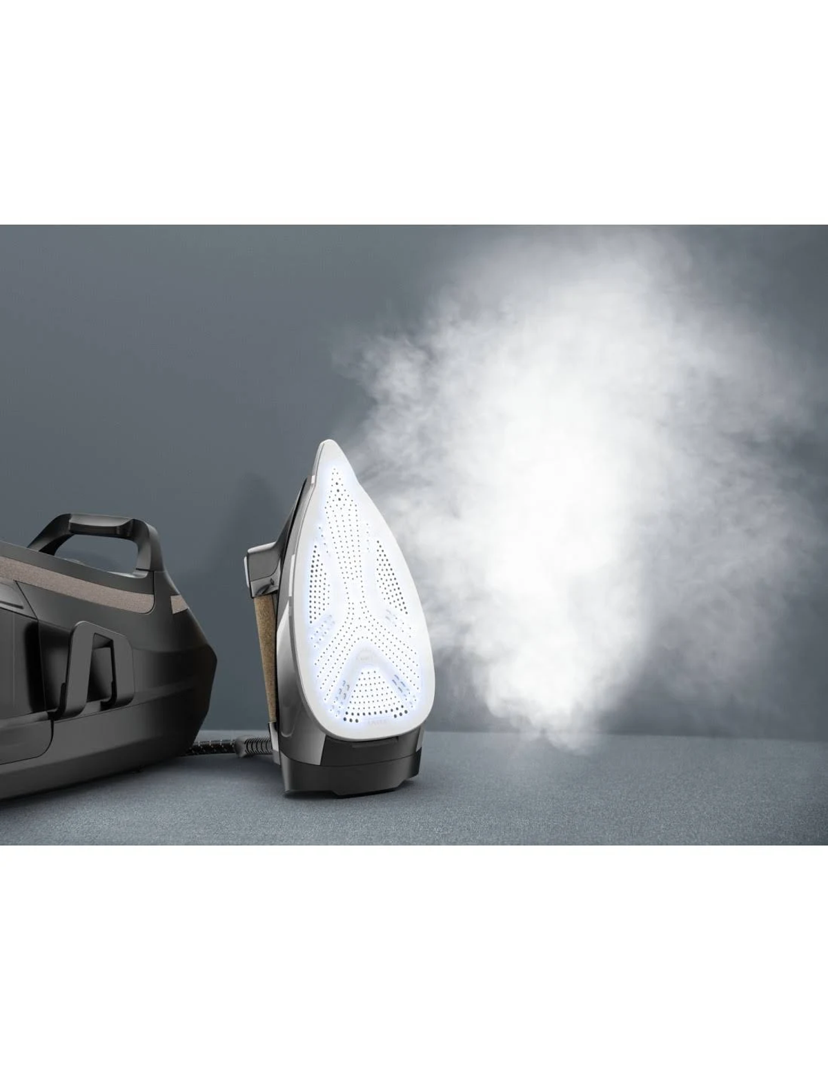 Plancha vaporizando. Plancha negra y blanca. Sale vapor. Fondo oscuro.