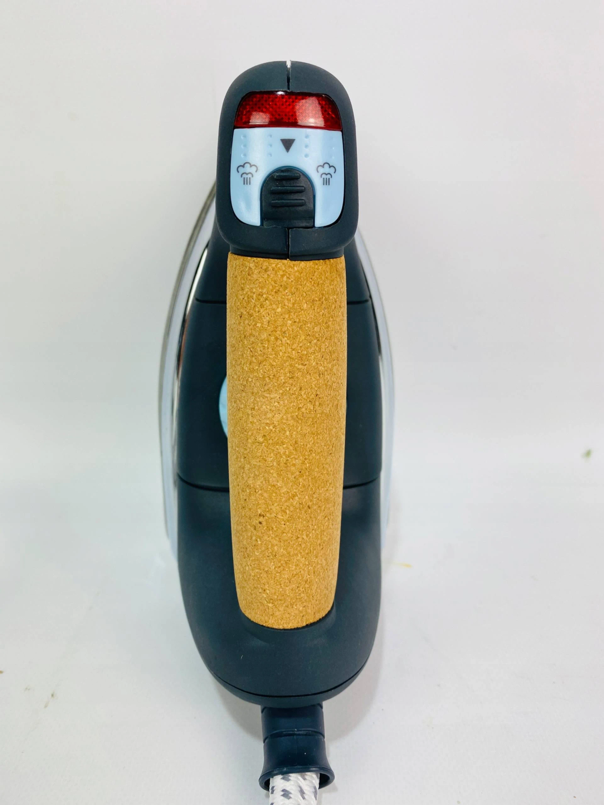 Vista superior de una plancha. Negra con mango de corcho. Controles de vapor y temperatura arriba.