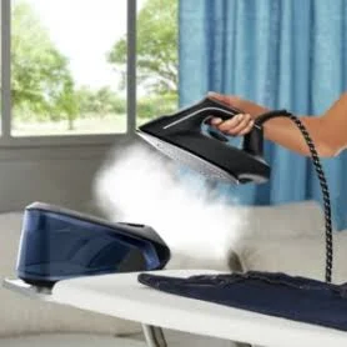 Una persona planchando con una plancha negra. El vapor es visible mientras la plancha.
