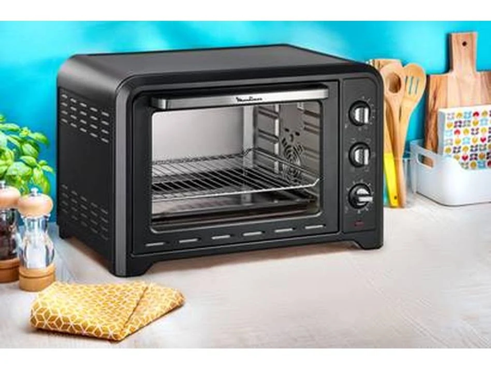 Forno tostapane nero su superficie in legno. Manopole e griglia argentata visibili.