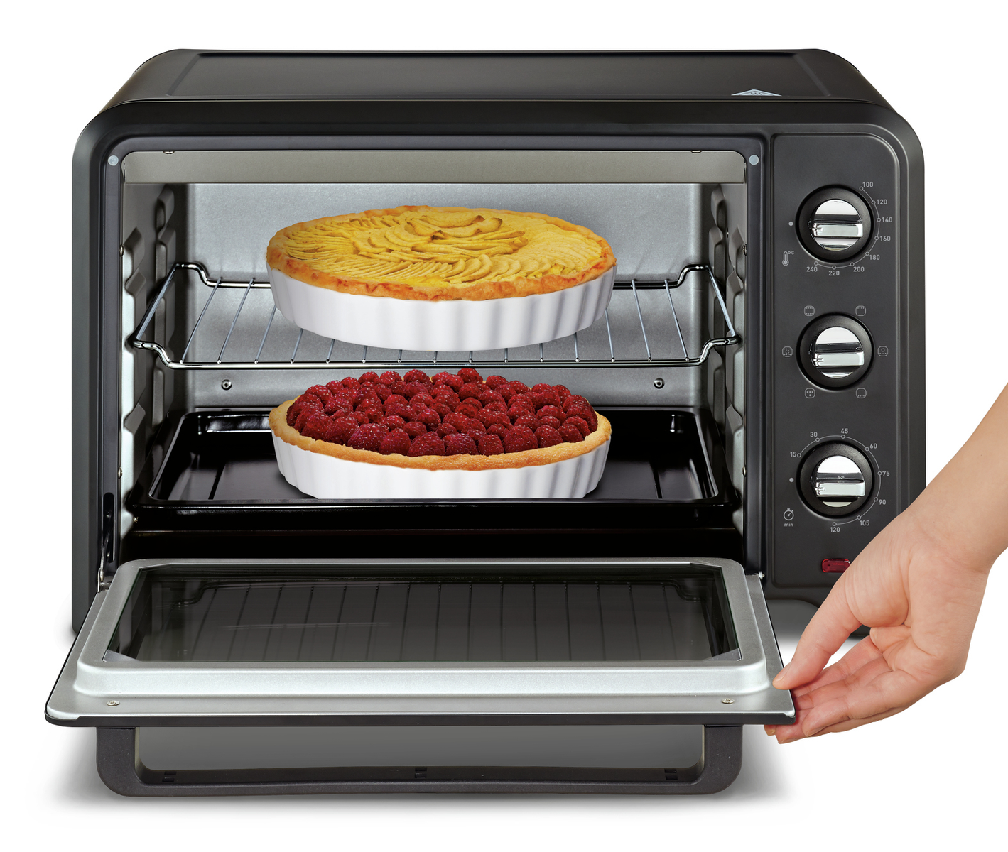 Czarny piekarnik z dwiema tartami w środku i ręką otwierającą drzwi piekarnika.