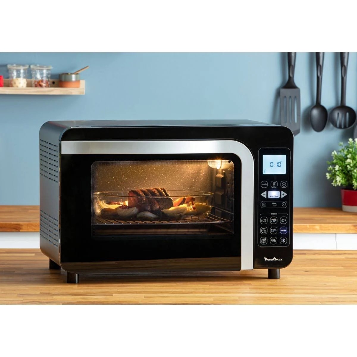 Un forno a microonde nero con cibo all'interno. Il cibo è in una pirofila di vetro, illuminato.