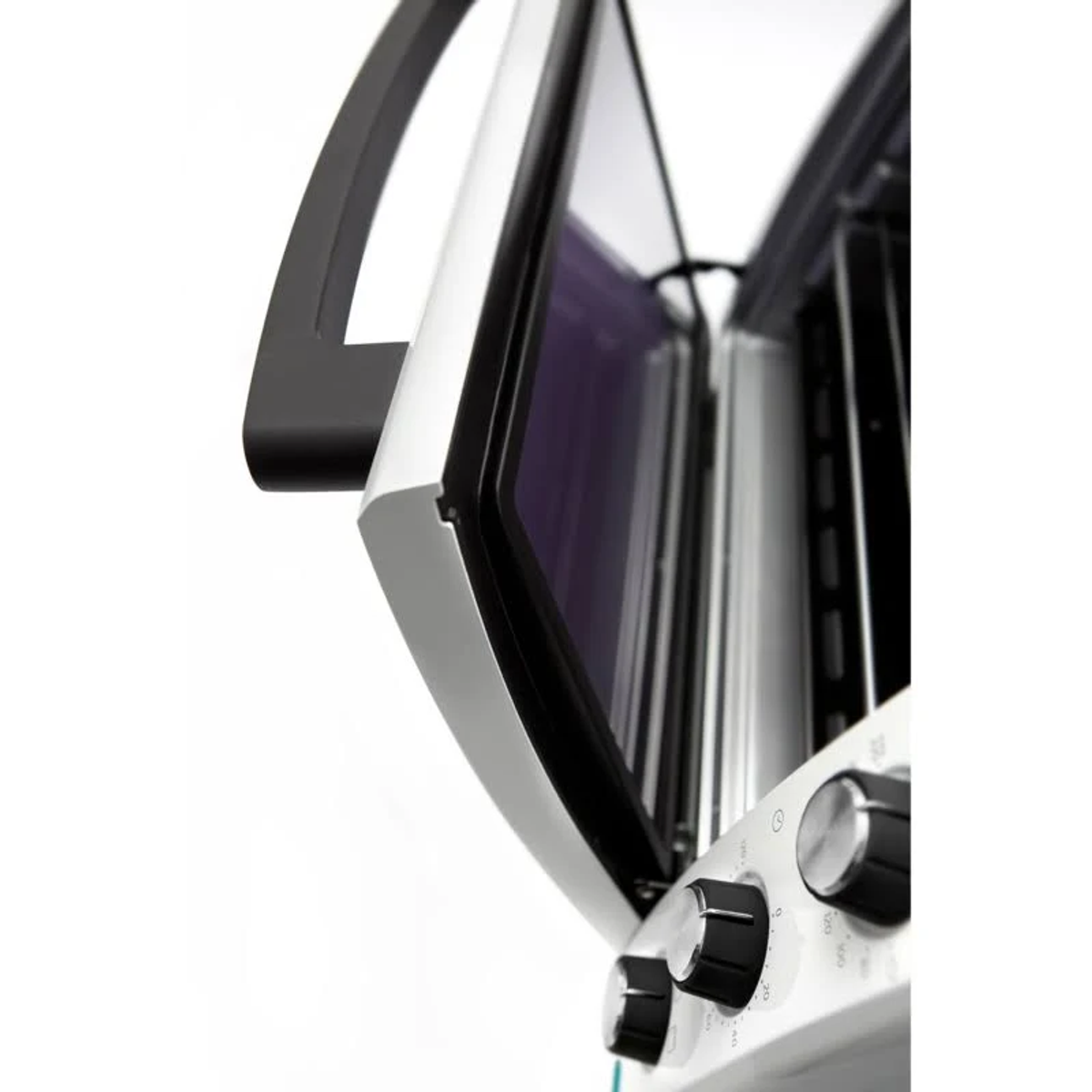 Zbliżenie białych drzwi piekarnika, otwartych, aby odsłonić wnętrze, widoczne pokrętła.