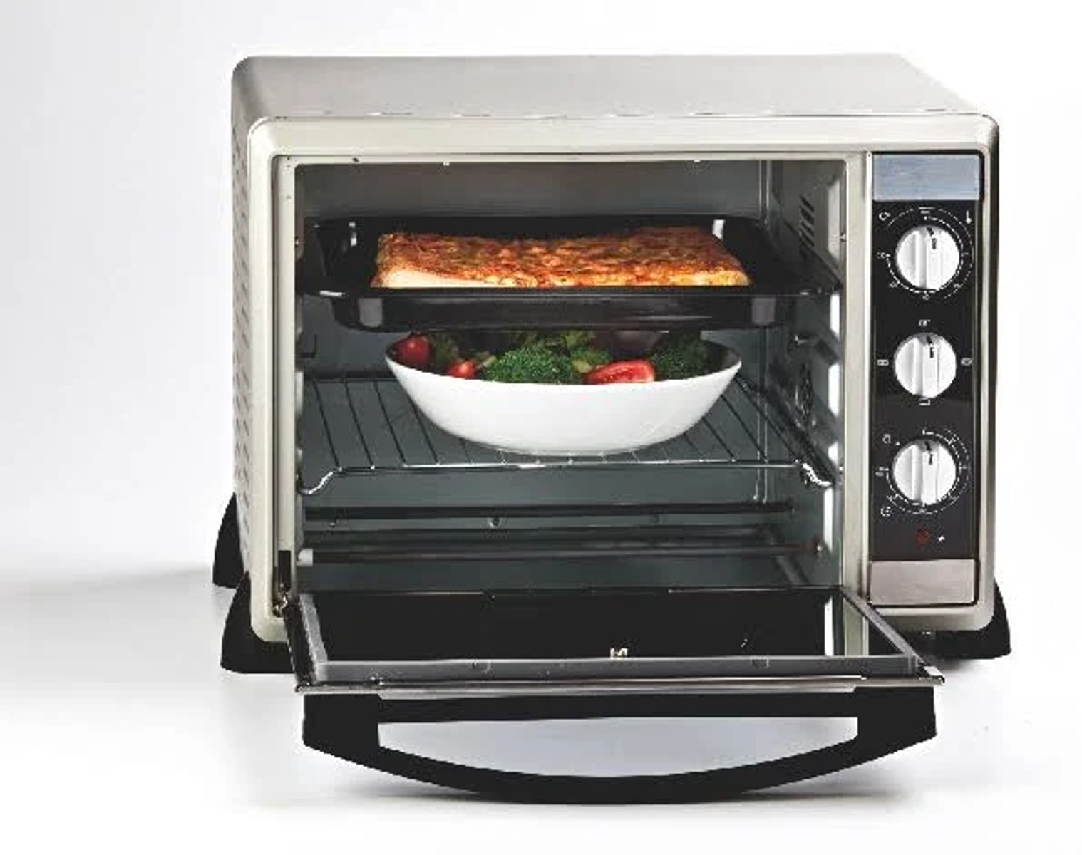 Piekarnik z pizzą i warzywami w środku, z otwartymi drzwiami.