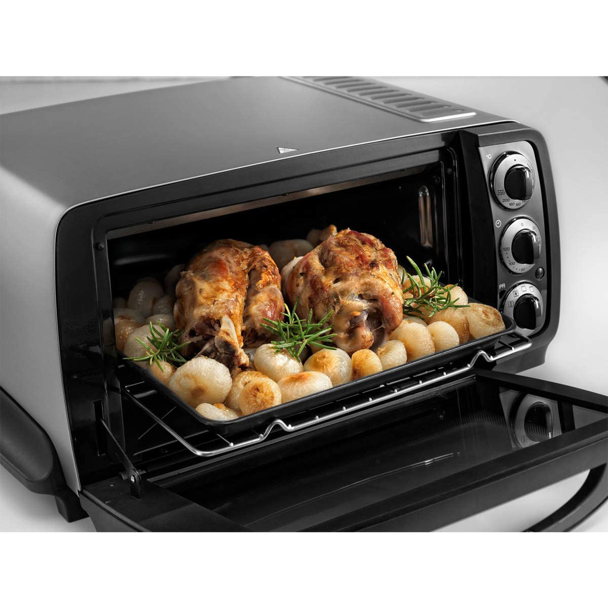 Piekarnik z pieczonym kurczakiem i cebulą na tacy. Drzwi piekarnika są otwarte, tło jest białe.